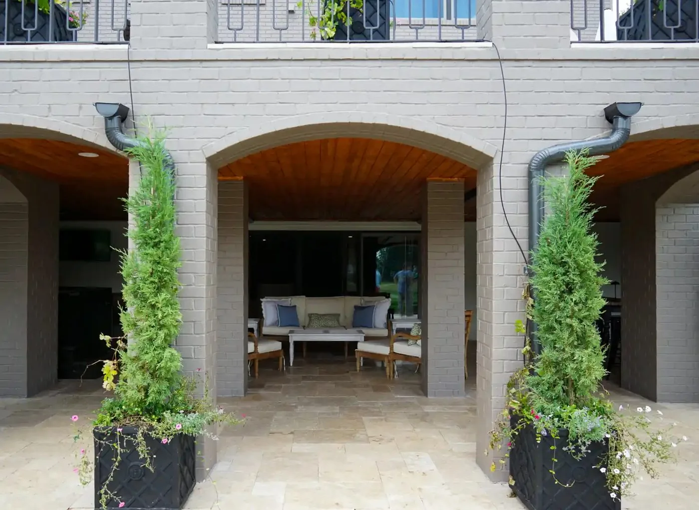 A brick arcade and travertine terrace across the back of a home