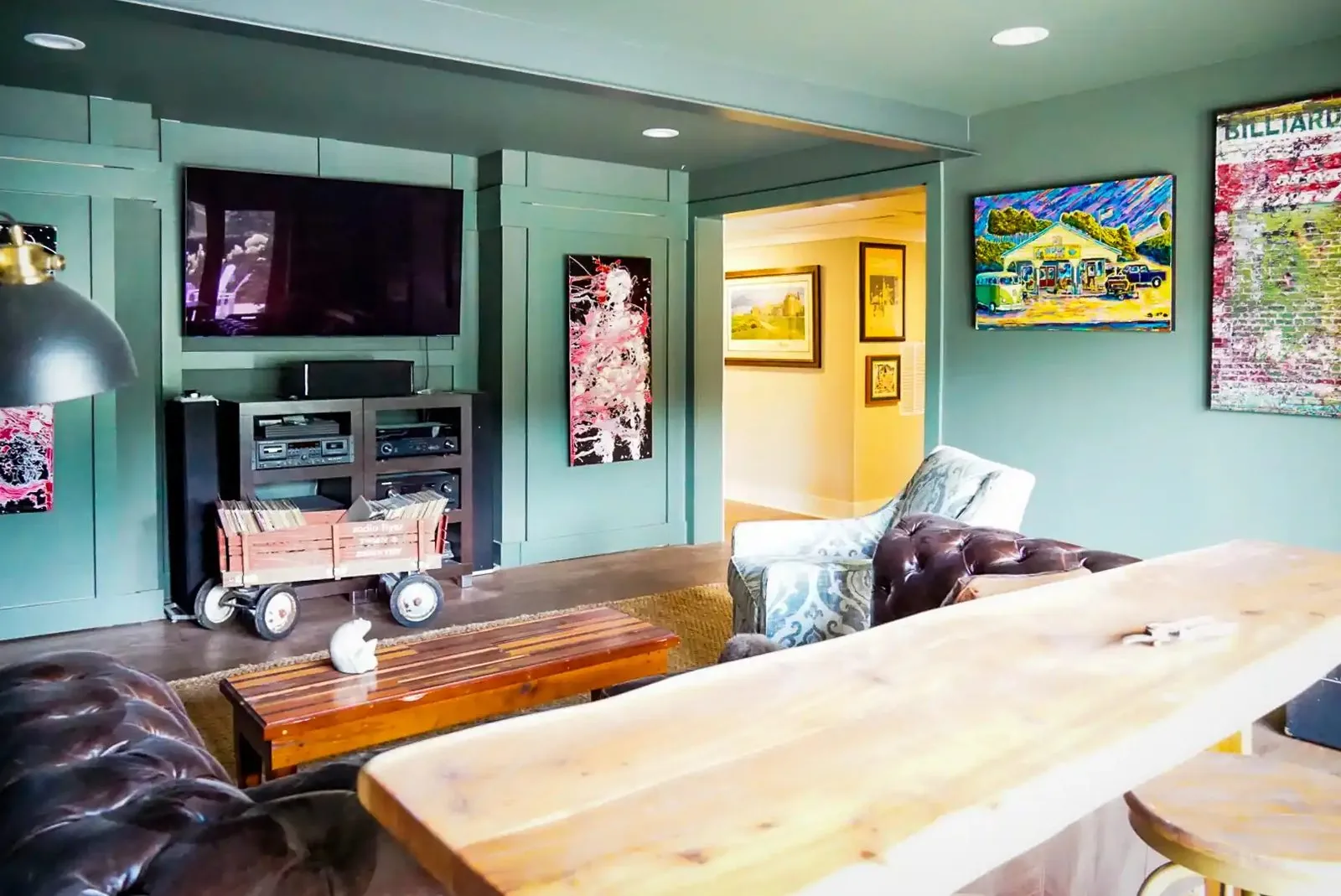 A finished basement living space with paneled walls, a wall-mounted television, and a live-edge bar counter